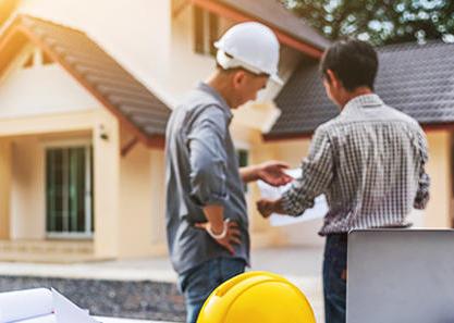 Man and contractor looking at blueprints and home